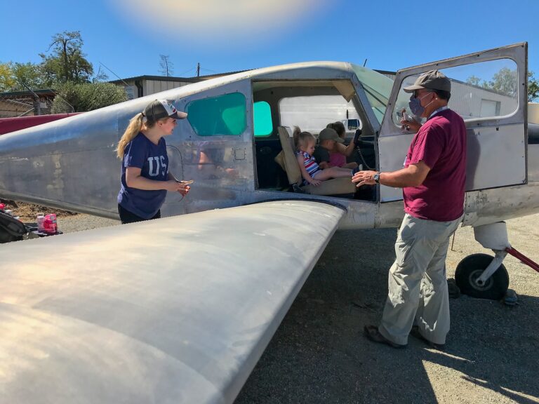 A docent using our Musketeer to demonstrate how flight controls work to a family visiting Wings of History